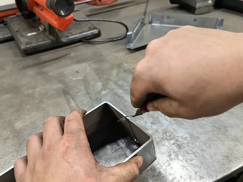 Manual deburring tool removing sharp edges from a metal tube