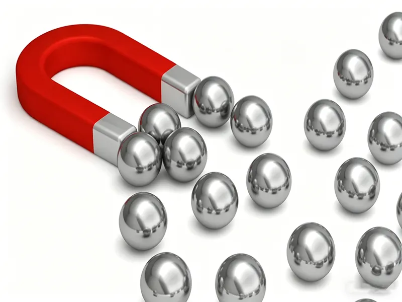 Magnet attracting metal balls to illustrate magnetic attraction and response