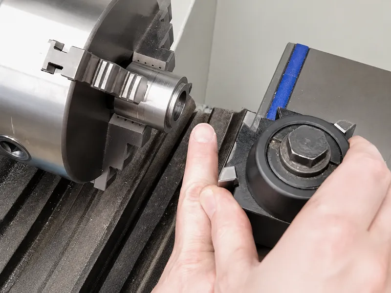 Manual lathe turning a metal workpiece with a cutting tool near the chuck