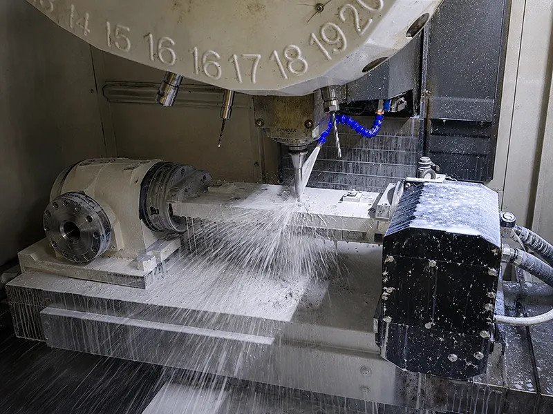 CNC milling machine cutting a metal workpiece with coolant during production