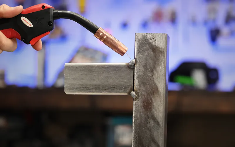 MIG torch positioning two metal sections with small tack welds before final welding