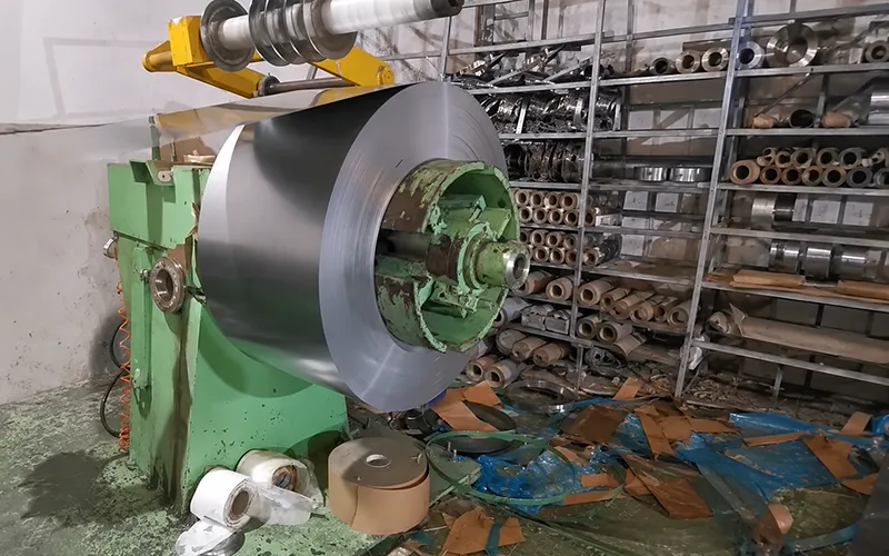 Types of Sheet Metals shown as a large metal coil being processed on industrial equipment