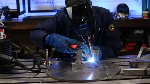 What Is Tack Welding shown in a workshop as a welder uses a welding torch to hold metal parts in position