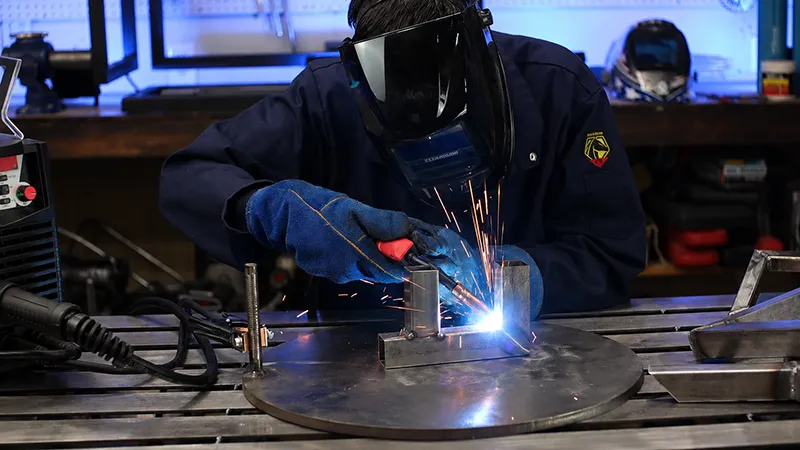 What Is Tack Welding shown in a workshop as a welder uses a welding torch to hold metal parts in position