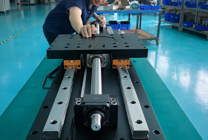 Technician assembling a precision linear stage with screw drive and guide rails