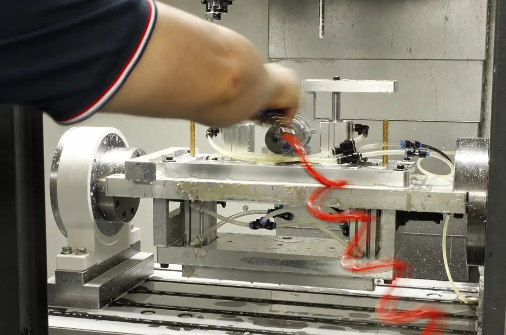 Operator working on a fixture inside a CNC machine, shown in a guide to material machinability.