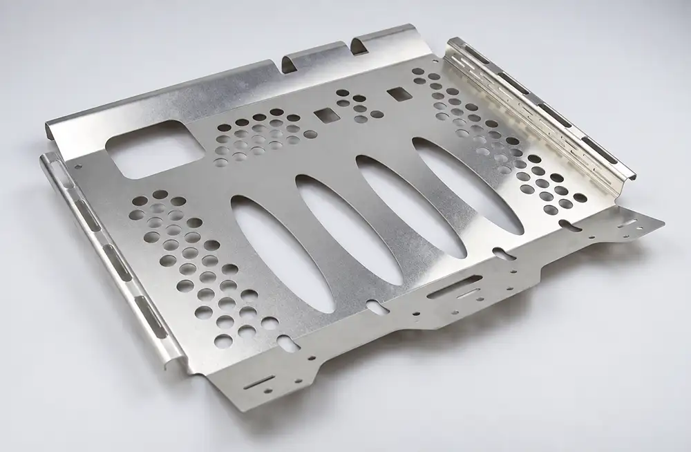 Sheet metal enclosure panel with folded edges, circular holes, and elongated cutouts on a white surface.